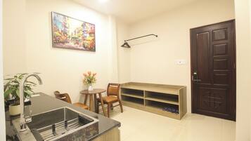 A compact living space with a kitchen area, a dining table, a seating arrangement, and a door.