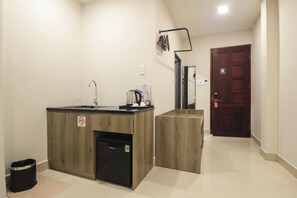 A hotel room with a kitchenette, a sink, a mirror, a door, and a trash bin. - DE LUSTORA II (CAU ONG LANH WARD)