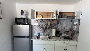 Cozinha compacta com geladeira, micro-ondas, pia e armários.
