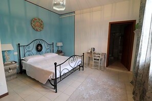 A bedroom with a bed, bedside tables, a lamp, a clock, and a door leading to another room. - Locanda Del Musso Con Ristorante (Adria)
