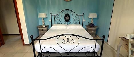 A bed with a metal frame and white bedding, two bedside tables with lamps, and a wall clock.