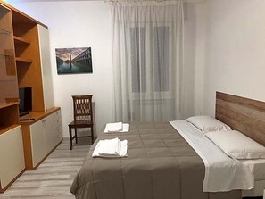 A hotel room with a bed, a chair, a TV, and a painting on the wall. - Locanda Del Musso Con Ristorante (Adria)