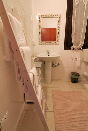 A bathroom with a white bathtub, a sink, a mirror with a decorative frame, and a towel rack. - Locanda Del Musso Con Ristorante (Adria)