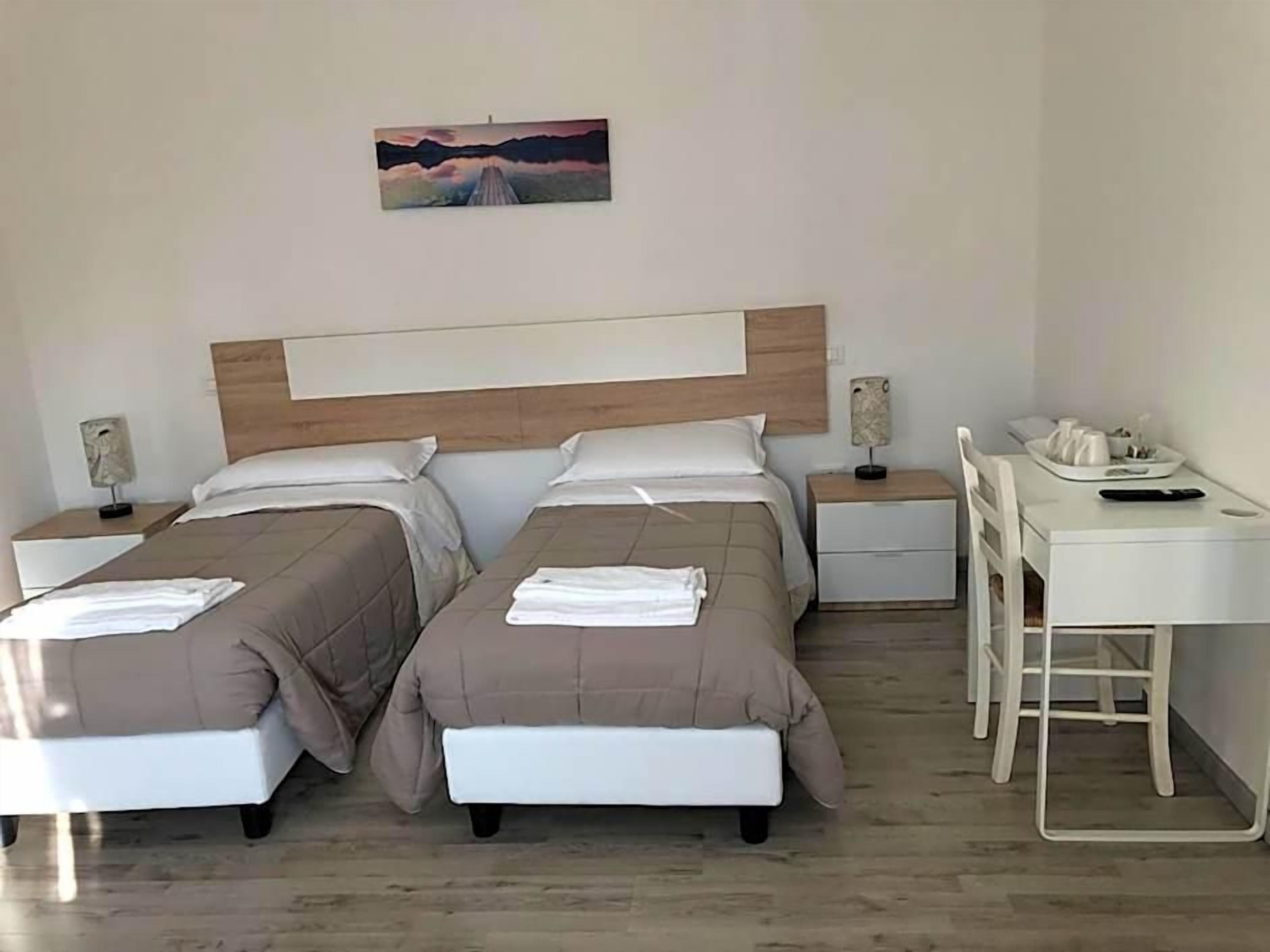 A hotel room with two beds, a desk, and a chair.