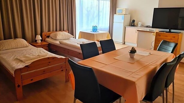 Una habitación de hotel con una cama, un escritorio, un televisor y una mesa de comedor con sillas.