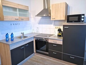 Una cocina moderna con estufa, horno, microondas y armarios de madera.