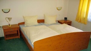 A single bed with a wooden frame and white bedding in a room with green carpeting. - Hotel Kraichgauidylle (Malsch)