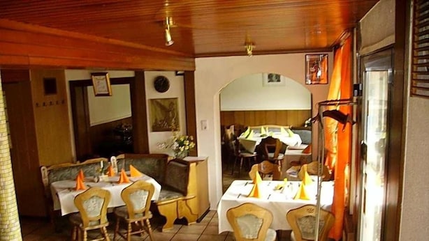A dining area with tables and chairs, a refrigerator, and a clock on the wall. - Hotel Kraichgauidylle (Malsch)