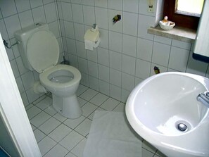 A bathroom with a toilet, sink, and tiled walls. - Hotel Kraichgauidylle (Malsch)