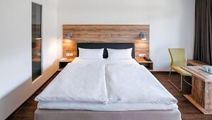 A hotel room with a large bed, a wooden headboard, bedside lamps, a desk, and a chair. - Restaurant Landhotel Winter (Gomadingen)