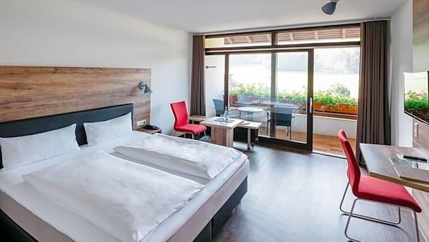 A hotel room with a large bed, a desk, and a view of the outdoors. - Restaurant Landhotel Winter (Gomadingen)