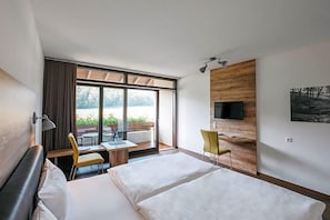 Une chambre d’hôtel équipée d’un lit, d’un bureau, d’une chaise, d’une télévision et d’une fenêtre donnant sur l’extérieur.