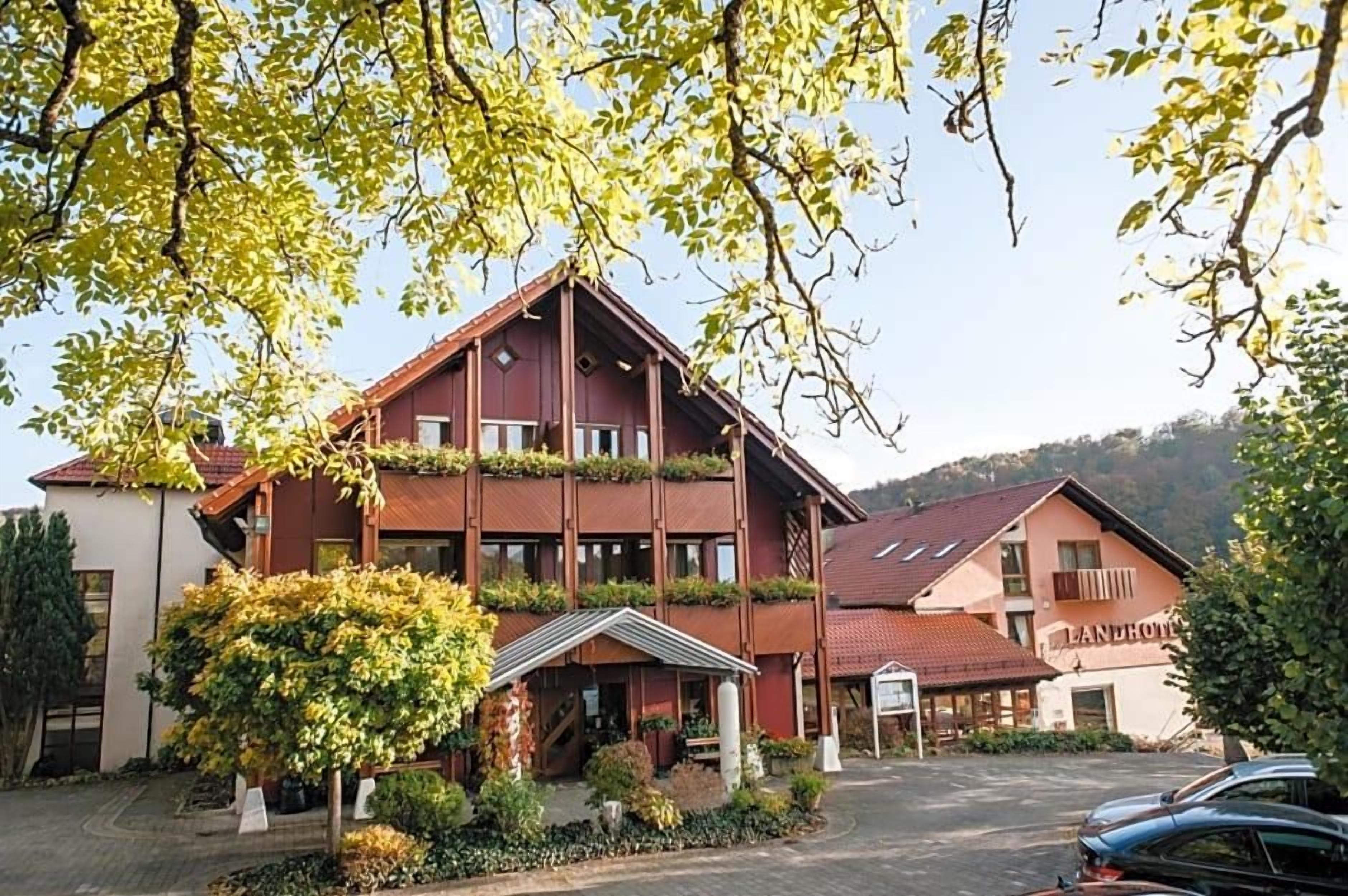 Ein mehrstöckiges Gebäude mit roter Fassade, einer überdachten Eingangsparte und einem Parkplatz.