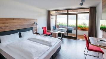 Ein Hotelzimmer mit einem großen Bett, einem Schreibtisch und Blick ins Freie.