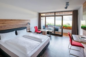 Une chambre d’hôtel avec un grand lit, un bureau et une vue sur l’extérieur.
