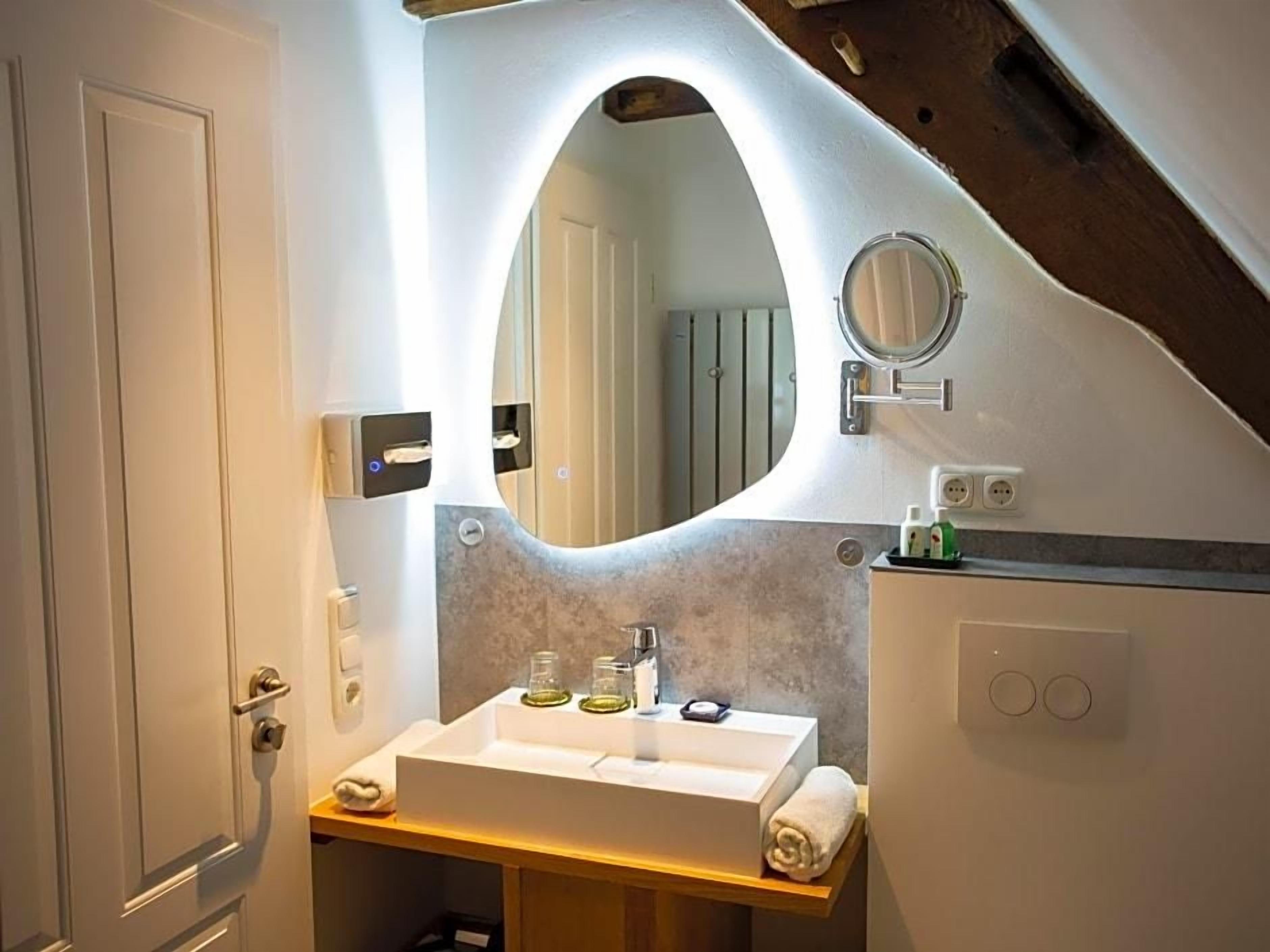 Een badkamer met een witte wastafel, een spiegel en een handdoek op het aanrecht.
