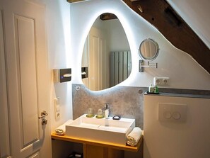 A bathroom with a white sink, a mirror, and a towel on the counter. - Altstadthotel Treysa (Schwalmstadt)