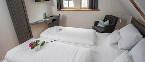 A bedroom with two beds, a desk, a chair, and a window with curtains.