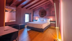 Un dormitorio con cama, mesita de noche, lámpara y una lámpara colgante.