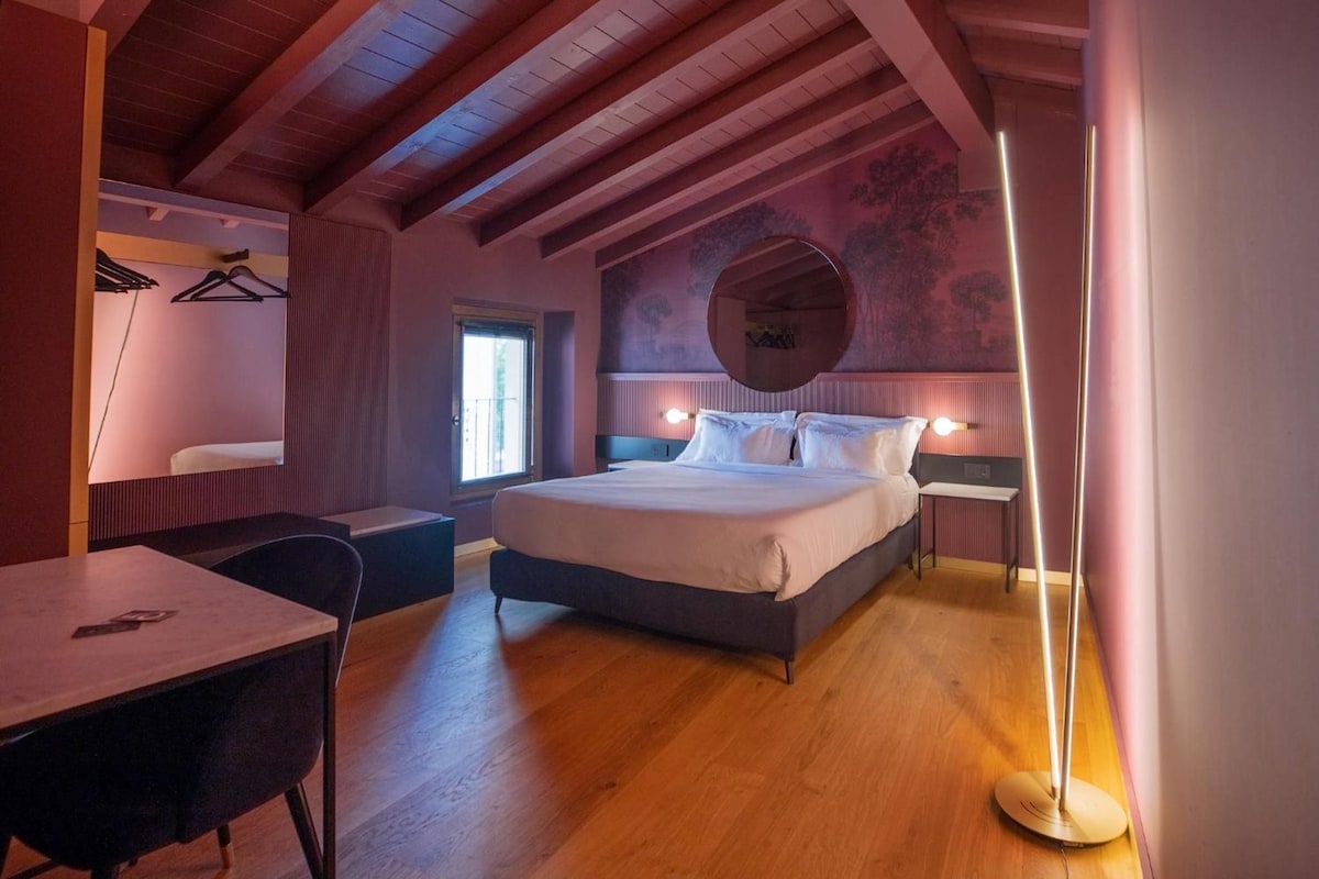 Un dormitorio con una cama, mesitas de noche, un escritorio y una silla.