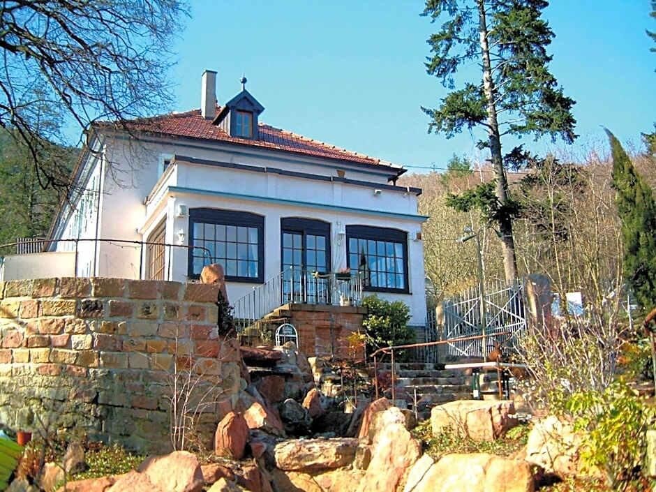 A two-story house with a stone wall, a metal staircase, and a clear sky.