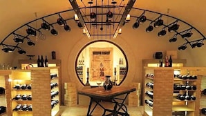 Una bodega con una mesa central, estanterías llenas de vino a cada lado y un arco circular.