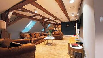 Un salón estilo loft con vigas de madera a la vista, techo inclinado y tragaluces.