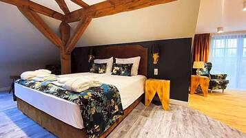 Un dormitorio con una cama grande, vigas de madera, una mesita de noche, una lámpara y vistas al exterior.