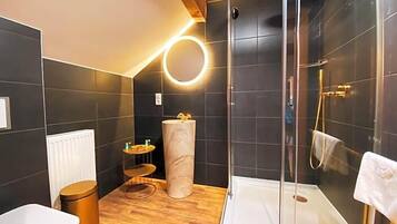 Un baño moderno con ducha, inodoro y una pequeña mesa redonda con una toalla.