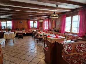 A restaurant with wooden beams, tiled floors, and tables set with red napkins. - Hotel Restaurant Zum Loewen (Jestetten)