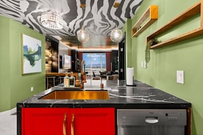 Una cocina moderna con encimera de mármol negro, armarios rojos y lavavajillas Bosch.