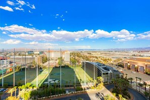 Un estadio con varias canchas deportivas, rodeado de edificios y palmeras.