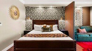 A hotel room with a large bed, a sofa, and a patterned wall.