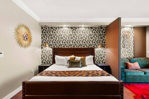 A hotel room with a large bed, a sofa, and a patterned wall.