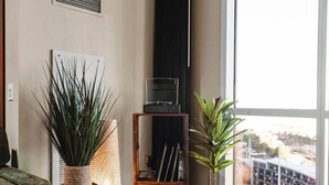 A room with a large window, a bookshelf, and two potted plants.