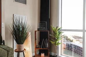 A room with a large window, a bookshelf, and two potted plants.