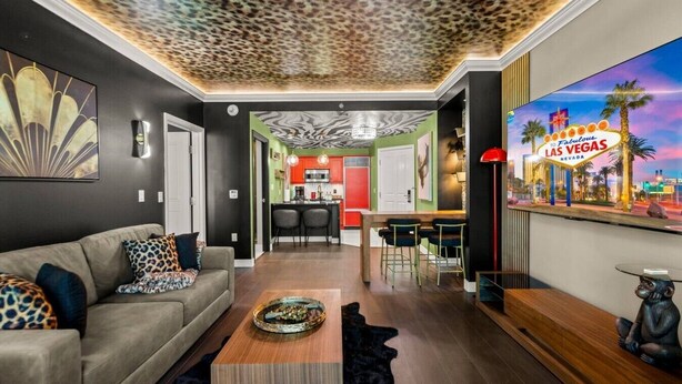 A modern living room with a sofa, coffee table, and a TV displaying a Las Vegas sign.