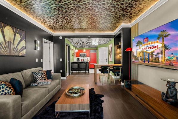 A modern living room with a sofa, coffee table, and a TV displaying a Las Vegas sign.