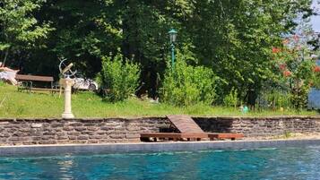 Ein Swimmingpool mit einer Steinmauer und einer Holzterrasse.
