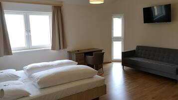 Ein modernes Hotelzimmer mit einem Bett, einem Schreibtisch, einem Sofa und einem Fernseher.