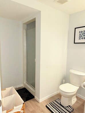 Un baño con inodoro, ducha y un cuadro en la pared.