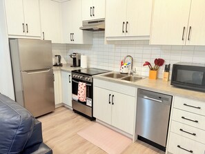 Una cocina moderna con electrodomésticos de acero inoxidable, armarios blancos y lavavajillas.