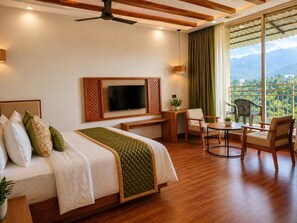 A hotel room with a bed, a TV, a desk, a chair, and a balcony with a view.