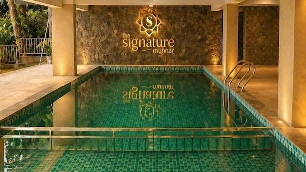 Piscina interna com piso ladrilhado e um logotipo na parede.