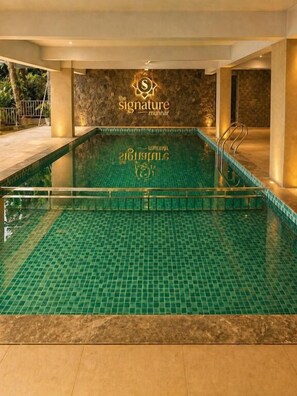 An indoor swimming pool with a tiled floor and a logo on the wall.