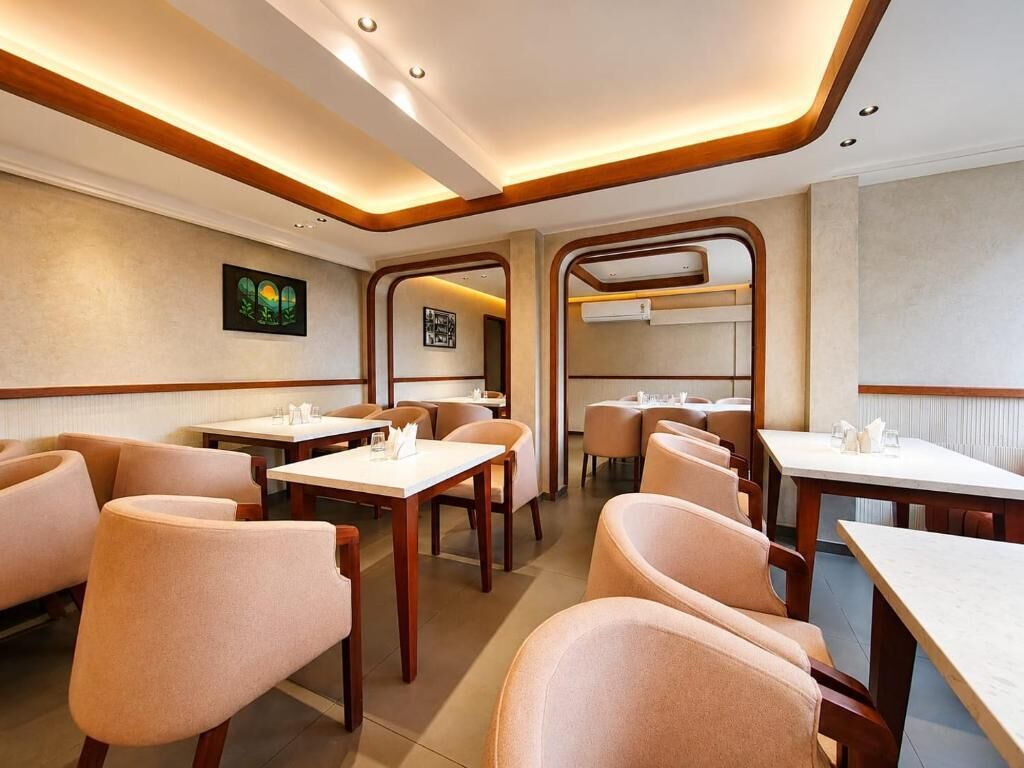Un interior de restaurante moderno con detalles de madera, varias mesas de comedor y sillas acolchadas.