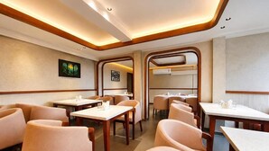 Interior moderno de restaurante com detalhes em madeira, várias mesas de jantar e cadeiras estofadas.