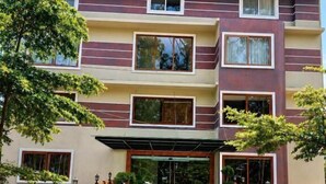 Um hotel com vários andares, telhado plano, entrada central e calçada pavimentada.