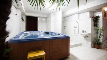 A modern bathroom with a hot tub, shower, and a small sink.
