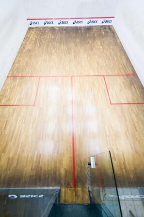En squashbane med trægulv og røde linjer.